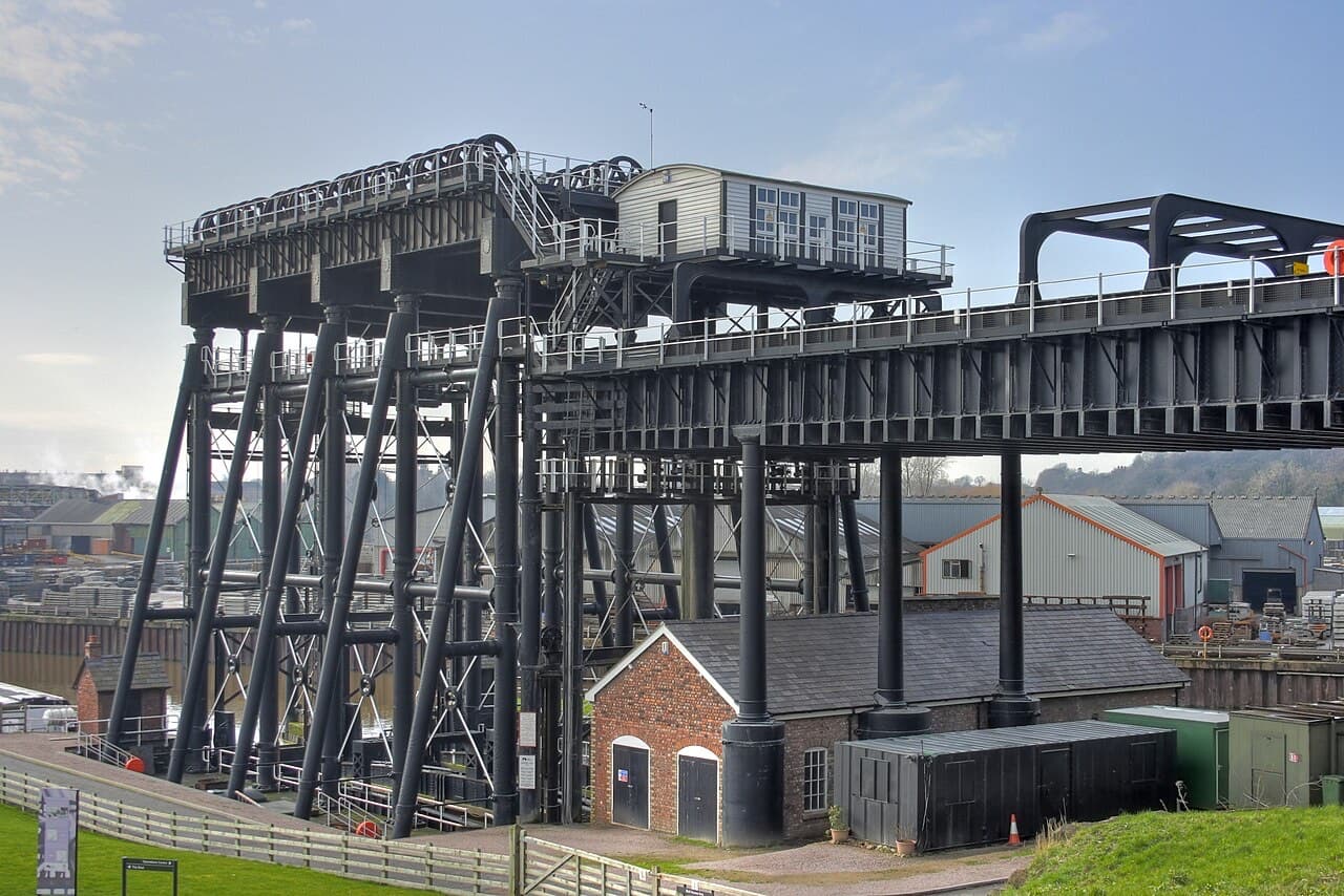 The black iron towers and high-level aqueduct of the Anderton Boat Lift rise over a small brick house beside the Trent & Mersey Canal in Cheshire.