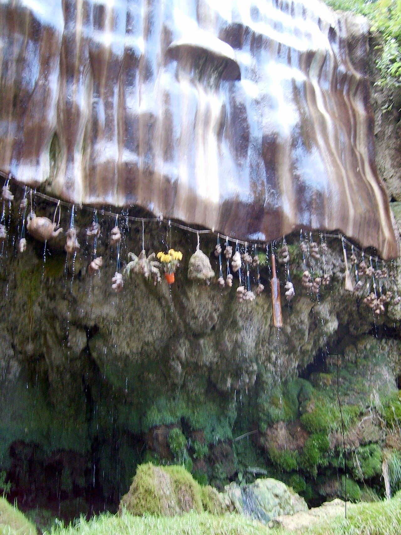 Water sheets over the striped flowstone of the Petrifying Well, where teddy bears and flowers hang on a line, slowly turning to stone.