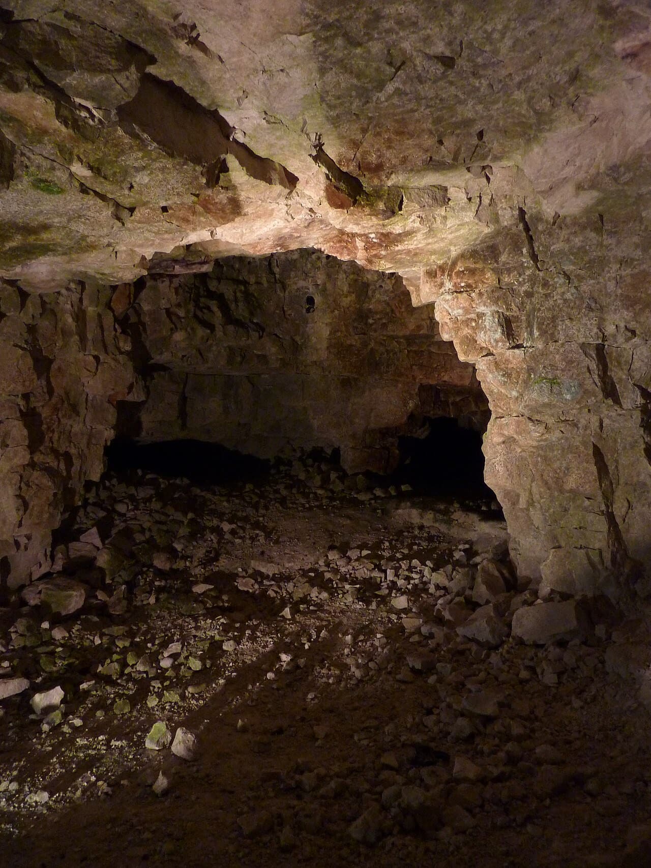 A low chalk gallery deep inside the Neolithic flint mine at Grime's Graves, its floor strewn with rubble and worked flint.