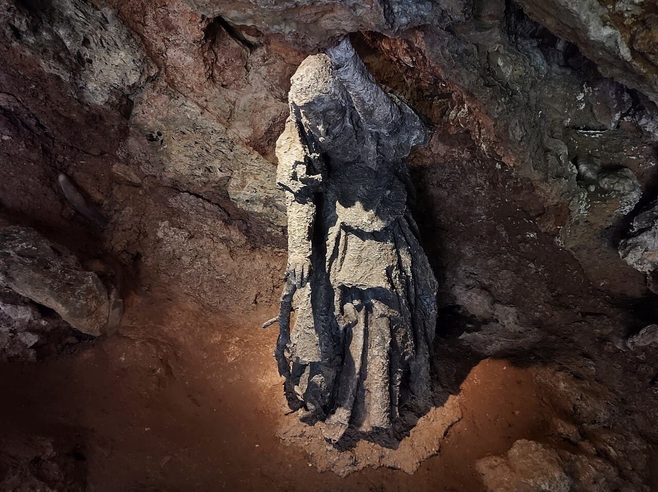 The dark calcified statue of Mother Shipton stands in a rocky alcove inside her cave beside the River Nidd.